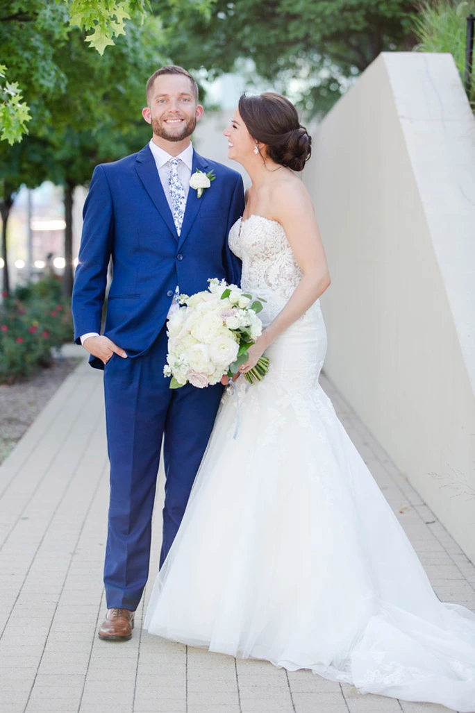 True Bride Bonnie, standing on a sidewalk with her husband, wearing her Martina Liana wedding dress, style 906.