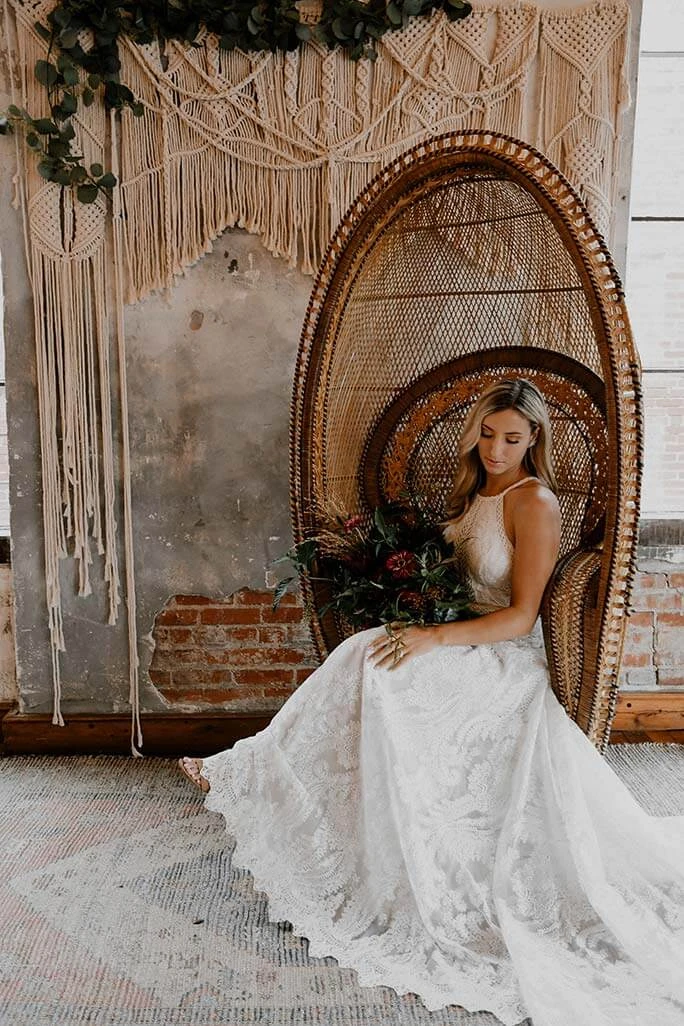 Boho bride sitting in her rattan chair, wearing the India wedding dress from the All Who Wander wedding gown collection