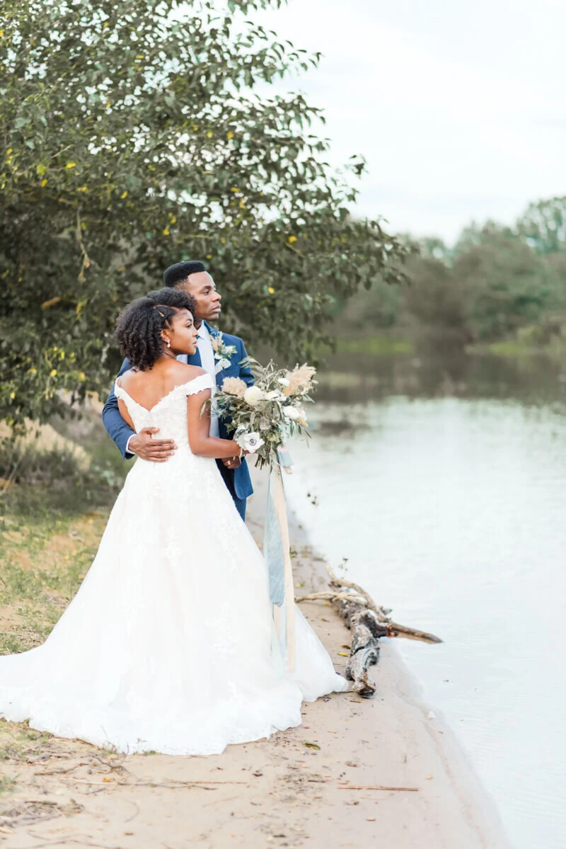 Trendy bride styled photo featuring groom and bride wearing essense of australia dress in style Style D2815 staring at the river