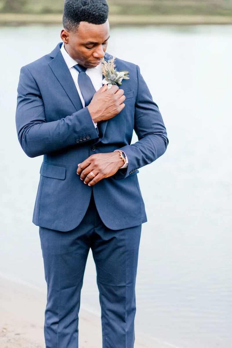 Trendy bride styled photo featuring groom fixing his suit
