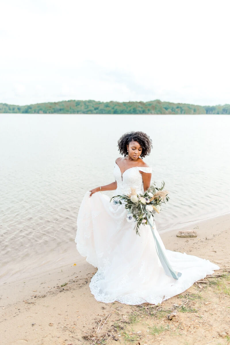 Trendy bride styled photo of bride wearing essense of australia dress in style Style D2815 holding bouquet with ocean background