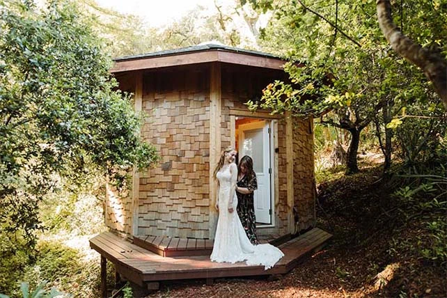 mother buttoning bride's gown in front of wooden cabin, martina liana 905