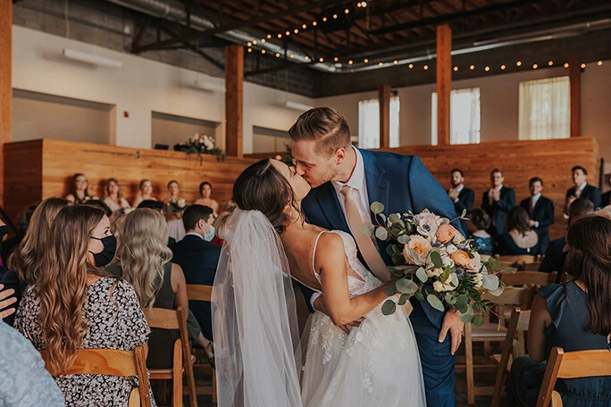 real bride and husband sharing kiss at wedding venue - style D2840 by essense of australia 