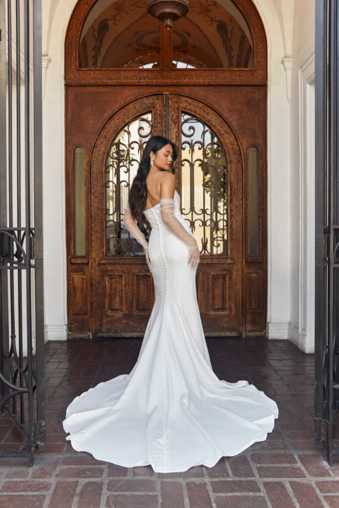 Bride in a strapless wedding dress with a sweetheart neckline, standing against a wooden door.