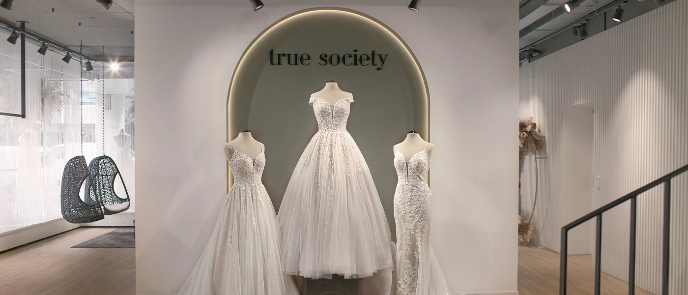 Display wall with 3 gorgeous floor length wedding gowns available for you to try on at our True Society bridal boutique in Zug.