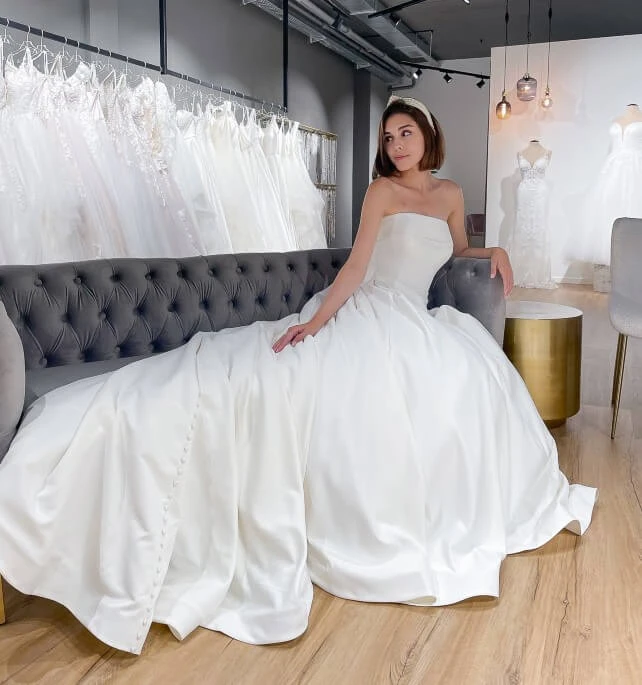 bride wearing a strapless ballgown while sitting on couch looking left, stella york 7045