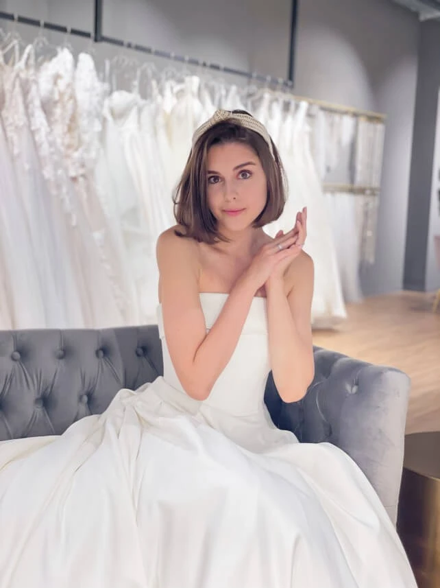 bride sitting on couch in bridal salon wearing strapless wedding gown, stella york 7045