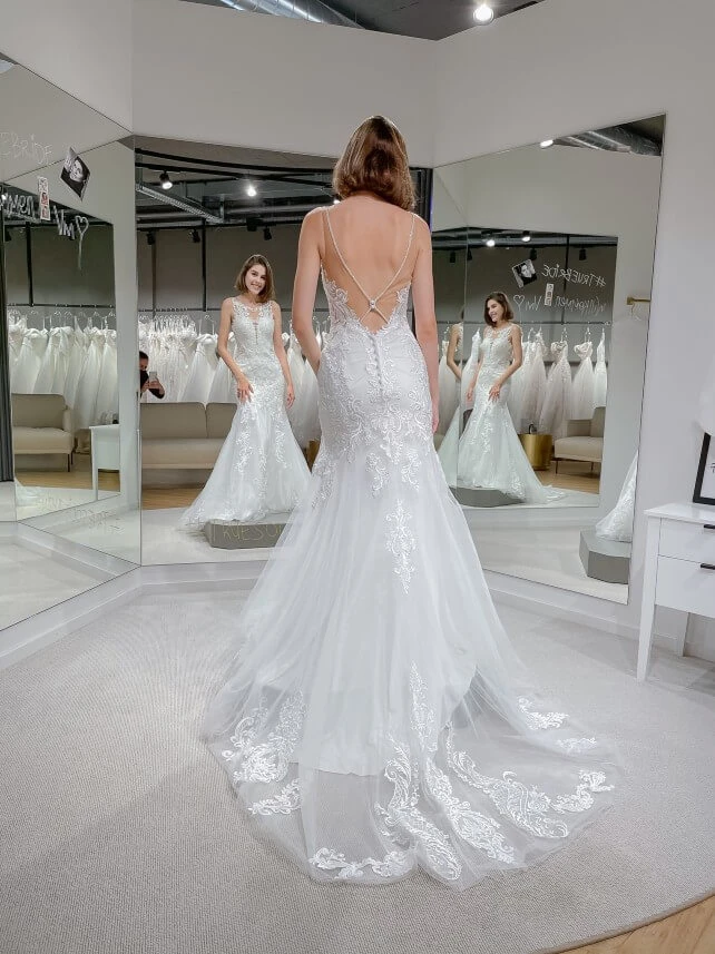 bride looking in mirror wearing a backless wedding gown, stella york 7325