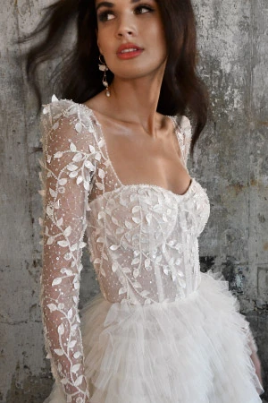 Latina woman wearing a designer wedding dress with long sleeves, 3D organic lace details and a corset bodice.