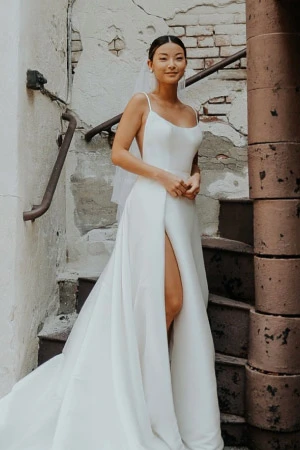 True Society bride wearing a simple, floor length wedding dress with thin straps and a slit in the skirt.