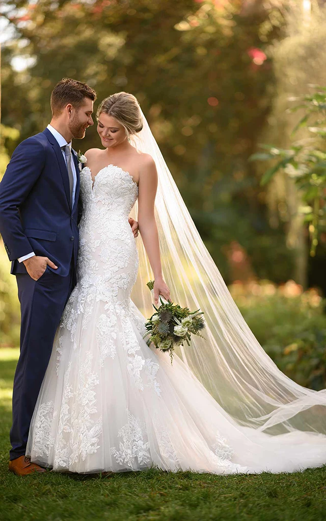 bride standing beside husband holding bouquet and wearing essense of australia gown d3044