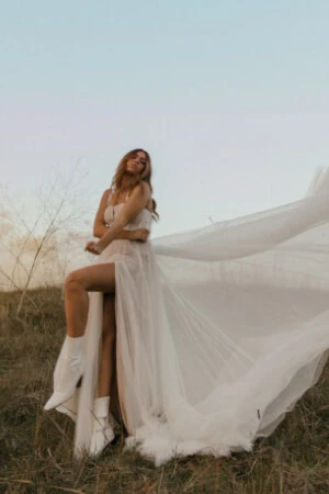 True Bride in a field wearing a boho wedding dress with a front slit.