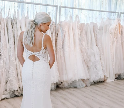 Back side view of a bride in a bridal shop trying on an affordable wedding dress.