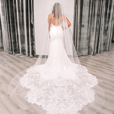 Back side view of a bride wearing a wedding dress and a floor length veil