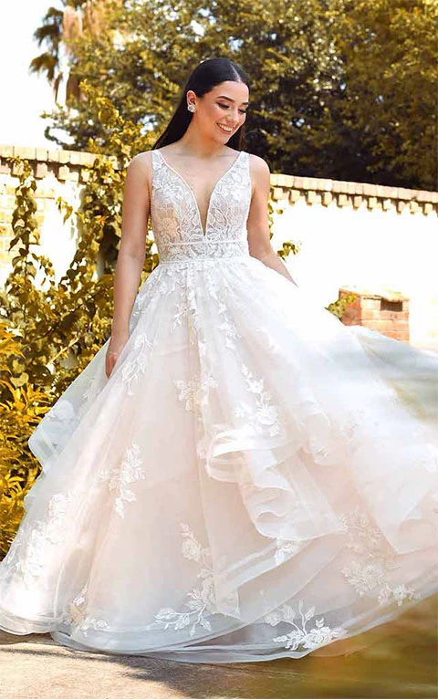 Bride wears sparkling princess ballgown wedding dress with plunging V-neckline.