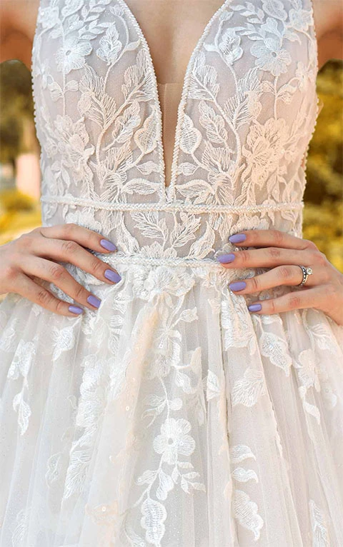 Close up detail of floral lace princess wedding dress with deep plunging neckline.