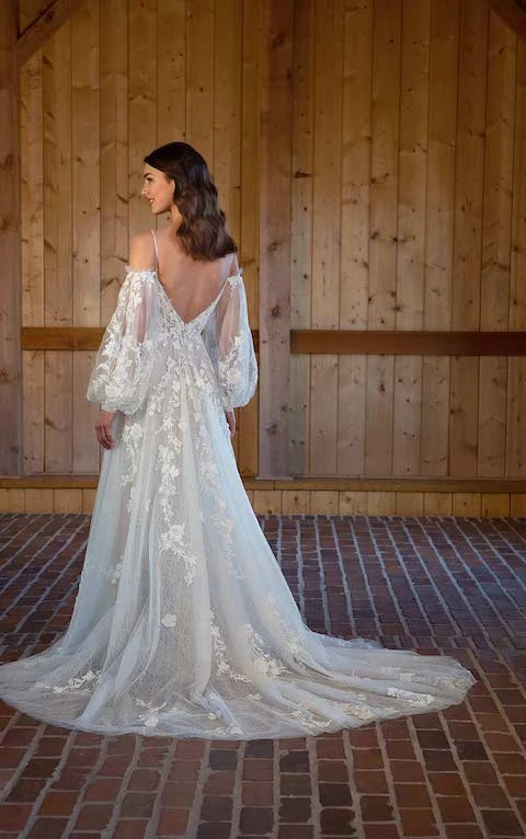 Bride wearing an bohemian off the shoulder long sleeved dress with lace and plunging back.