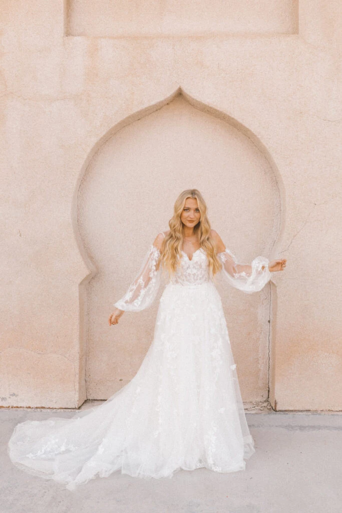 Bride wearing an bohemian off the shoulder long sleeved dress with lace and plunging back.