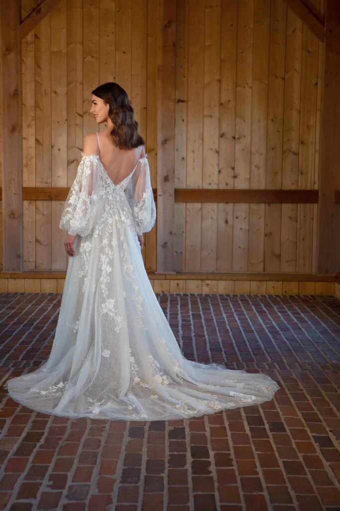 Bride wearing an bohemian off the shoulder long sleeved dress with lace and plunging back.