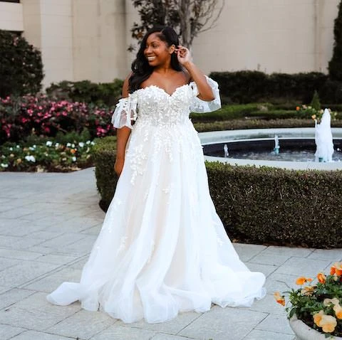 Plus sized bride wearing tulle wedding dress with lace bodice and sleeves