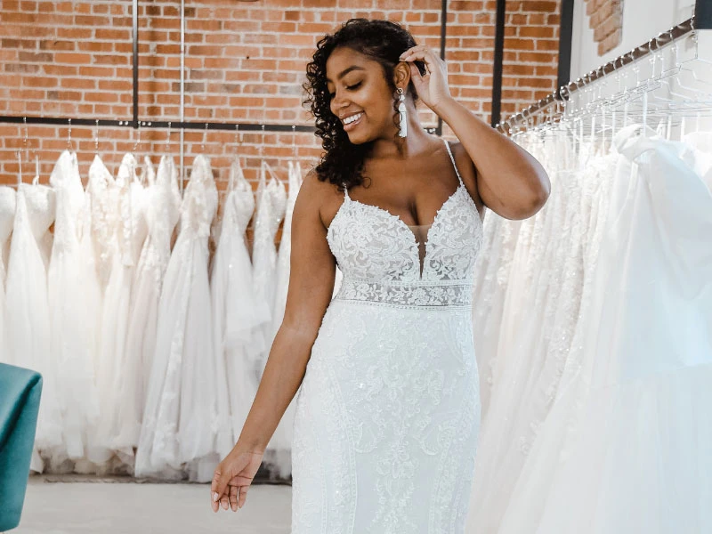 Woman of color bride, wearing a spaghetti strap lace wedding dress at her local True Society bridal shop.