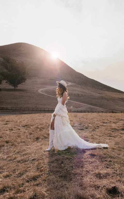 Bride wears boho floral wedding dress and wide-brimmed hat veil alternative.