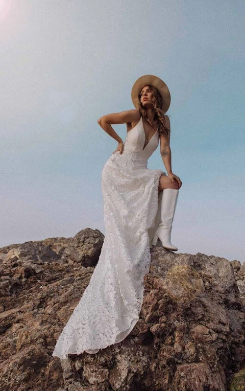 Bride wearing simple floral lace bohemian wedding dress and wide-brimmed bridal hat.