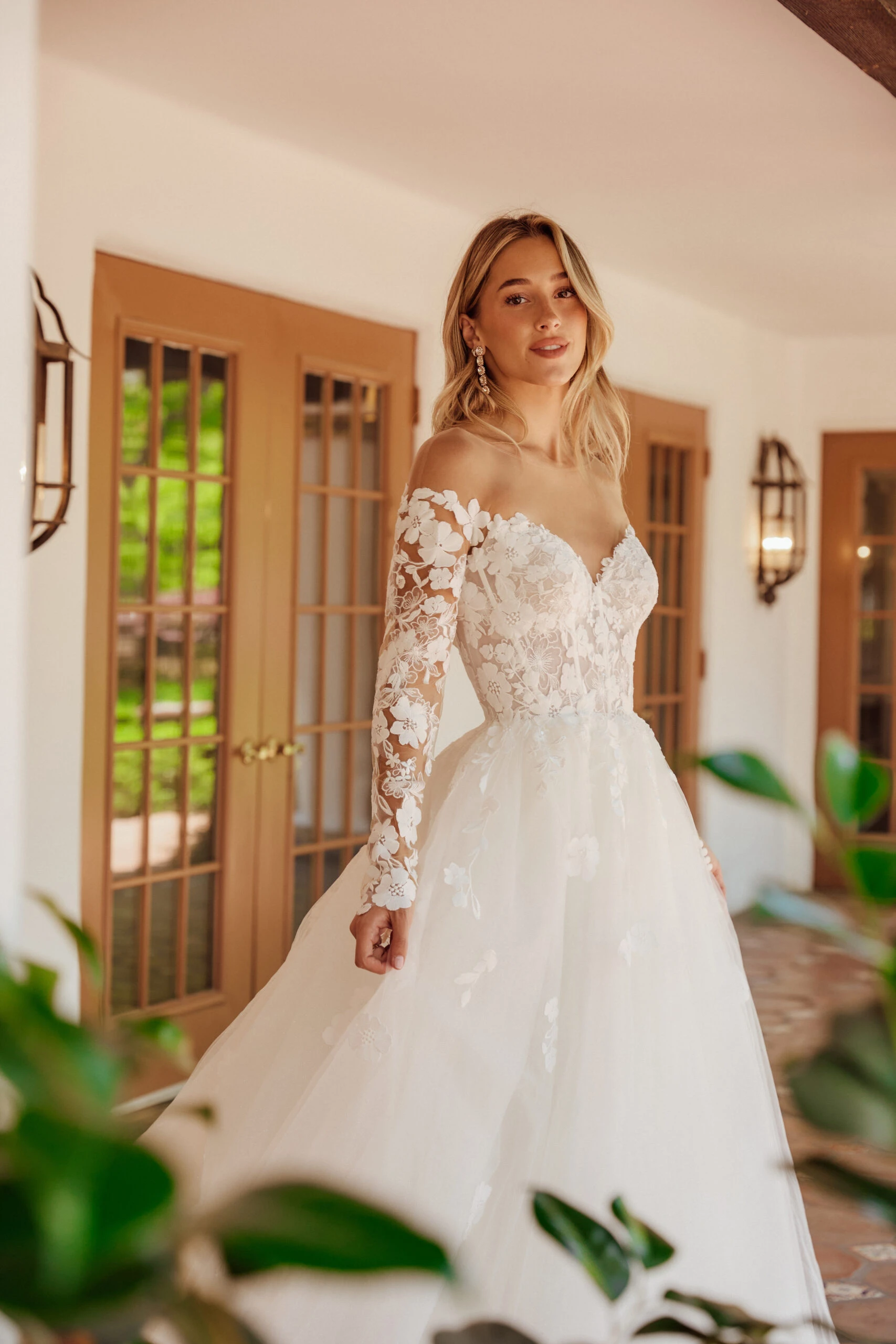 bride standing on a porch wearing an off-the-shoulder lace ballgown 