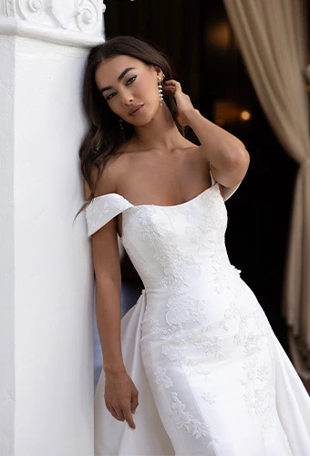 Bride wearing fit and flare wedding dress with off the shoulder straps and lace appliques