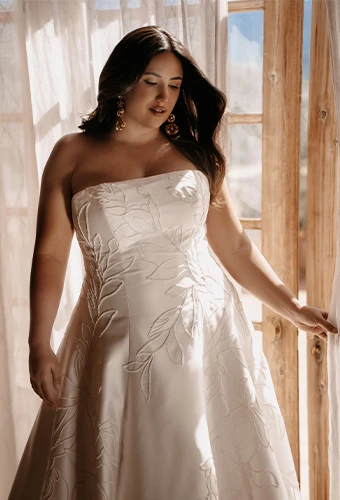 Plus size bride wearing strapless a line wedding dress with graphic lace and straight across neckline