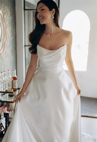 Bride wearing strapless a line wedding dress with scoop neckline and pearl details