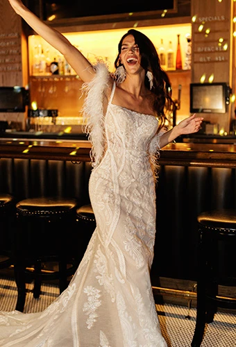 Bride wearing lace fit-and-flare wedding dress with side cutouts and spaghetti straps