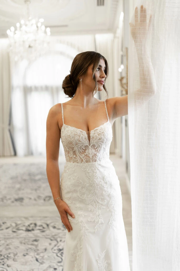 Bride wearing a elegant sweetheart lace fit-and-flare wedding gown in a white ballroom