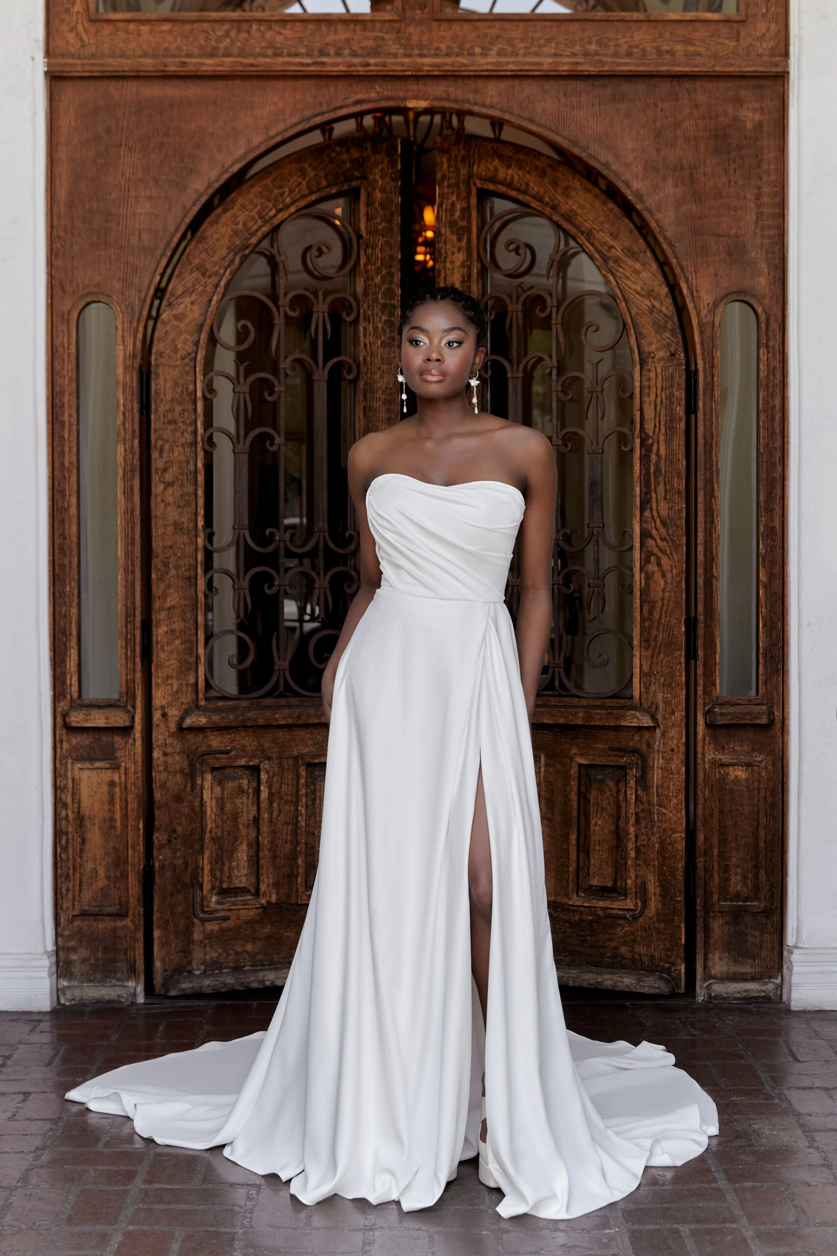 bride wearing a strapless simple wedding dress in a wooden doorway