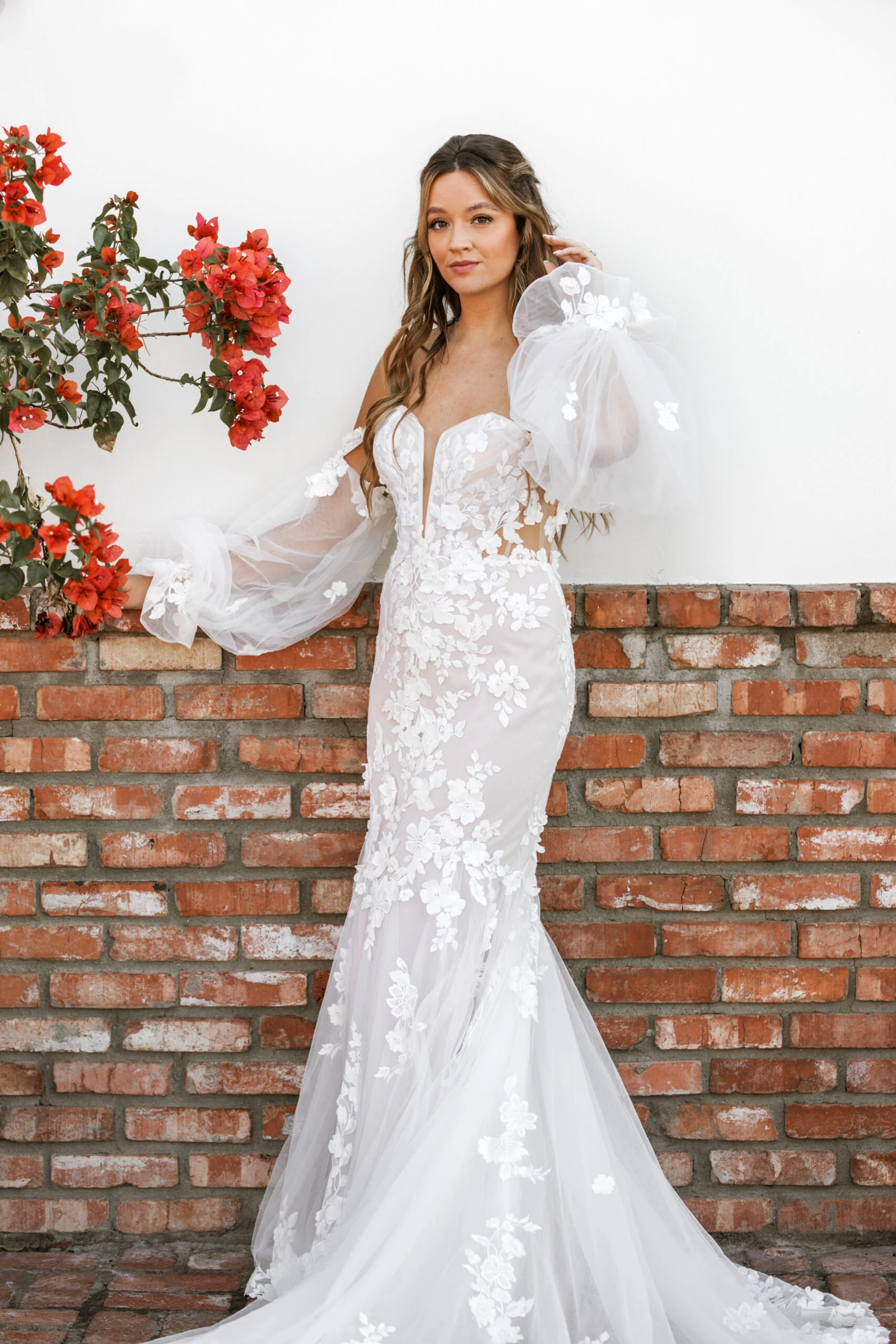 bride wearing off the should lace wedding dress with a brick wall behind