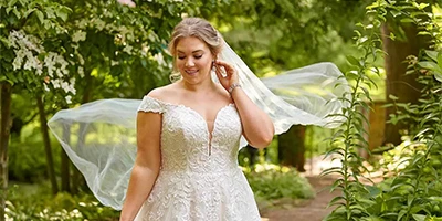Bride wears off-the-shoulder lace wedding dress and beautiful veil.