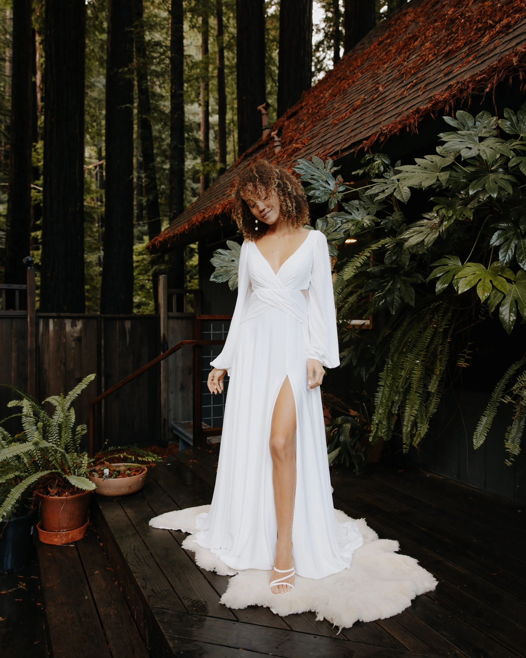 bride wearing an open back long sleeve wedding dress in a forest
