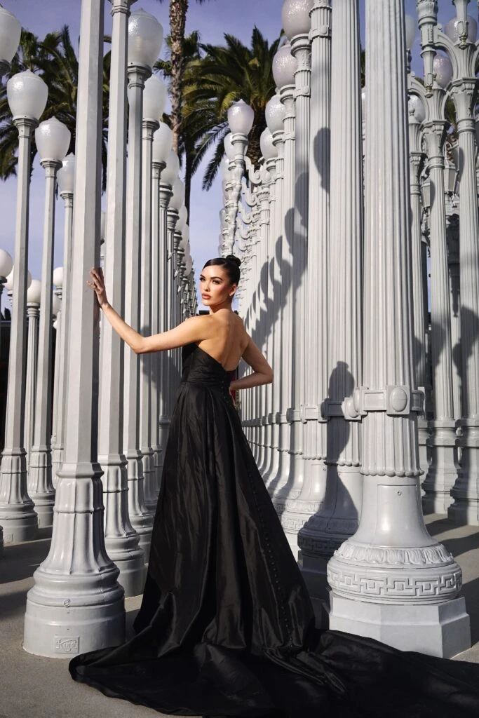 Back of bride wearing a black wedding dress standing next to light poles