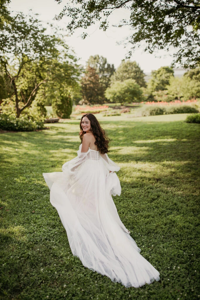 Bride running in the grass wearing a long sleeve off-the-shoulder dress
