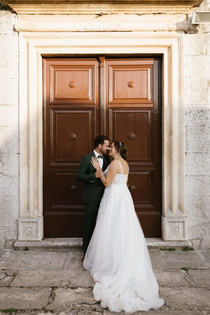 Bride and groom hugging in front of a door