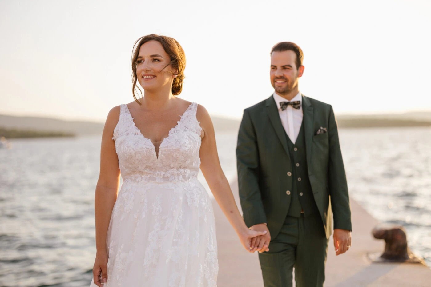 Bride and groom holding hands walking on a dock