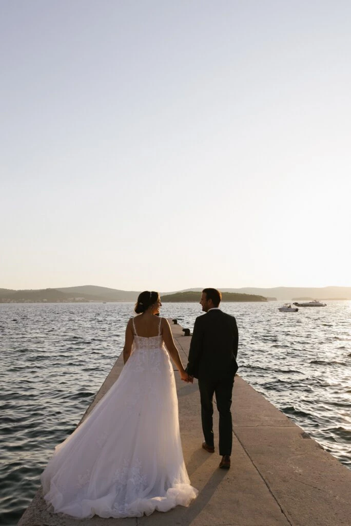 Bride and groom holding hands walking down a dock