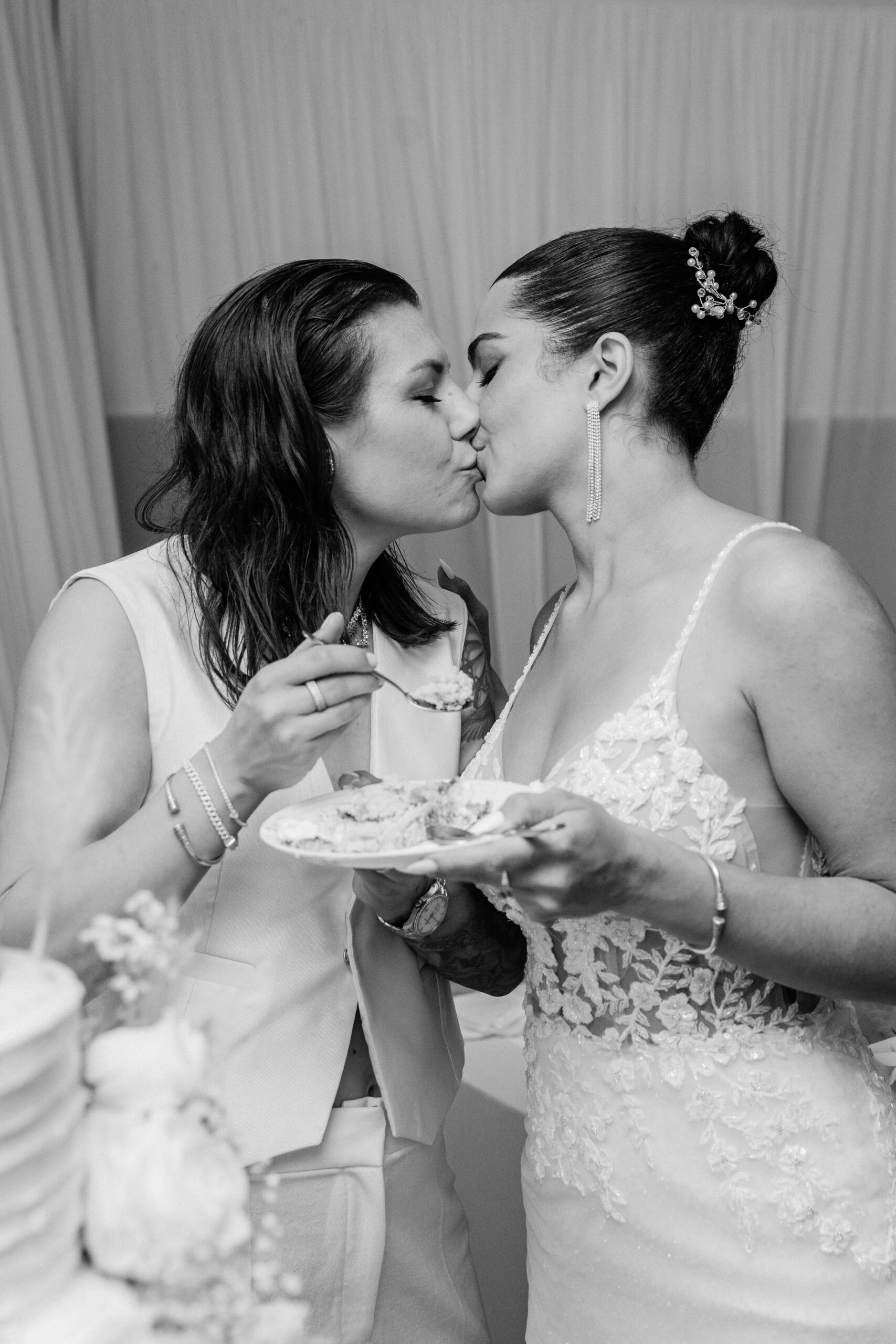true brides ramona and charlotte kissing while eating wedding cake - Martina Liana 1137