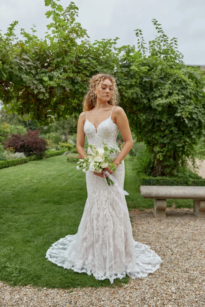 Bride wearing a lace mermaid wedding dress holding a bouquet of flowers 