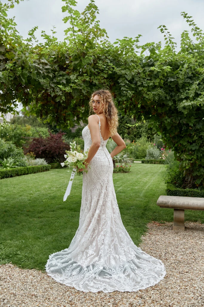 Back of Bride wearing a lace mermaid wedding dress holding a bouquet of flowers