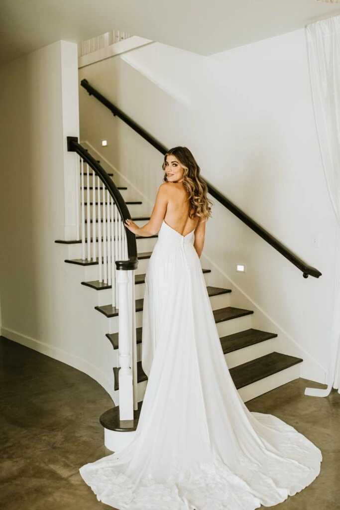 Bride wearing a wedding dress with long train walking up the stairs
