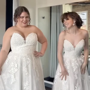 two brides wearing same wedding dress and smiling at each other