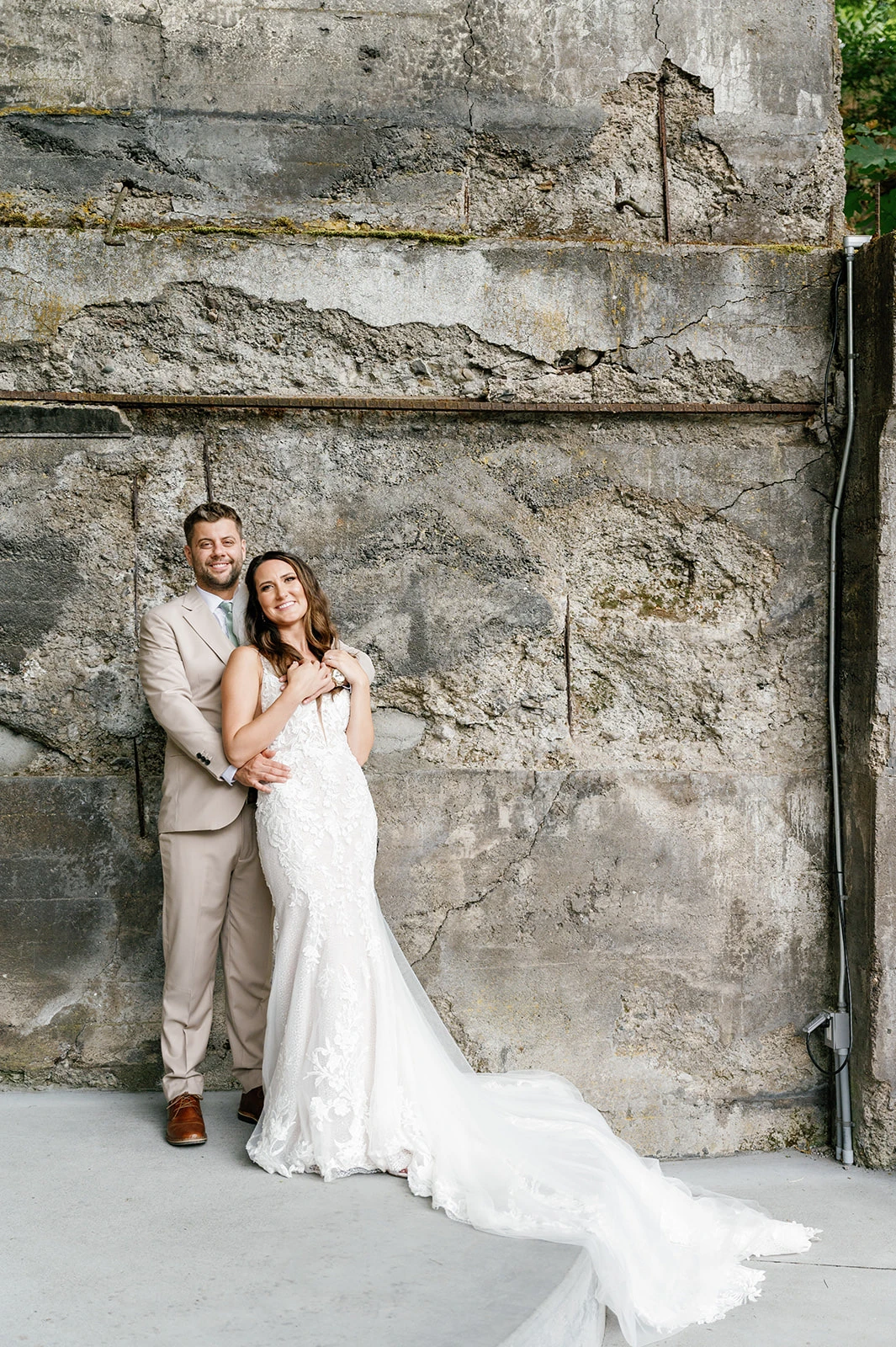 Groom and Bride embracing in front of a stone wall