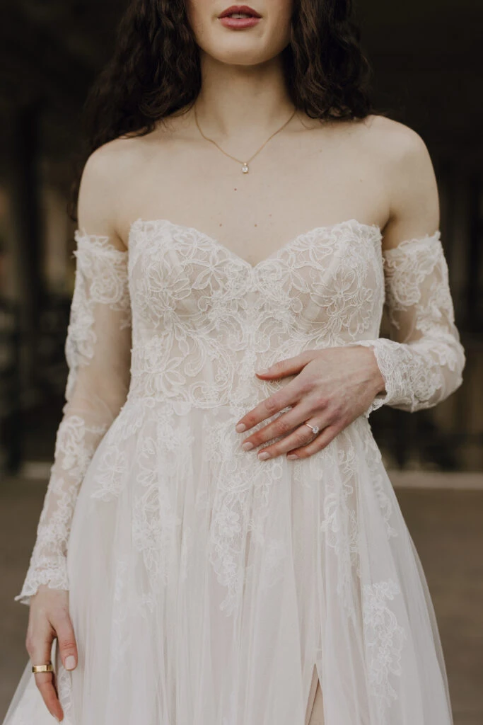 Close up of bride wearing a long sleeve off-the-shoulder wedding dress 