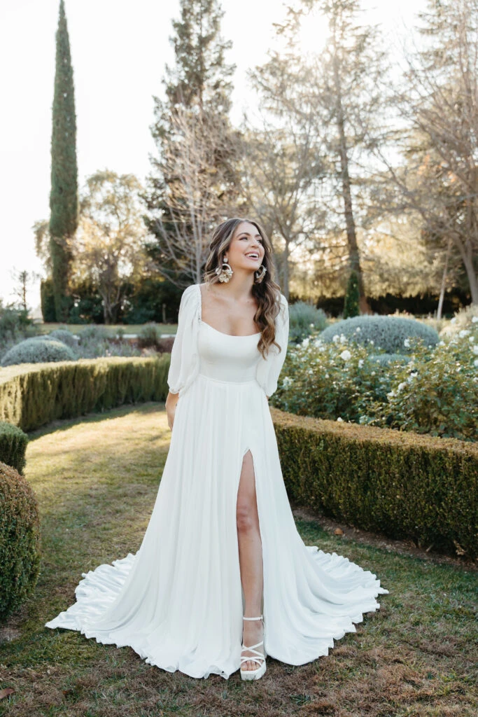 Bride wearing long sleeve bell sleeve wedding dress in a garden